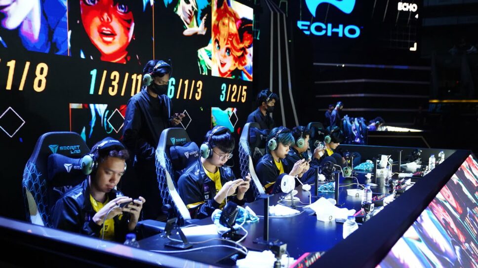 The Esports team, fresh from their time at Camp Cosmos, competes in a tournament. Each player is intensely focused on their device, with game stats displayed on a large screen behind them.