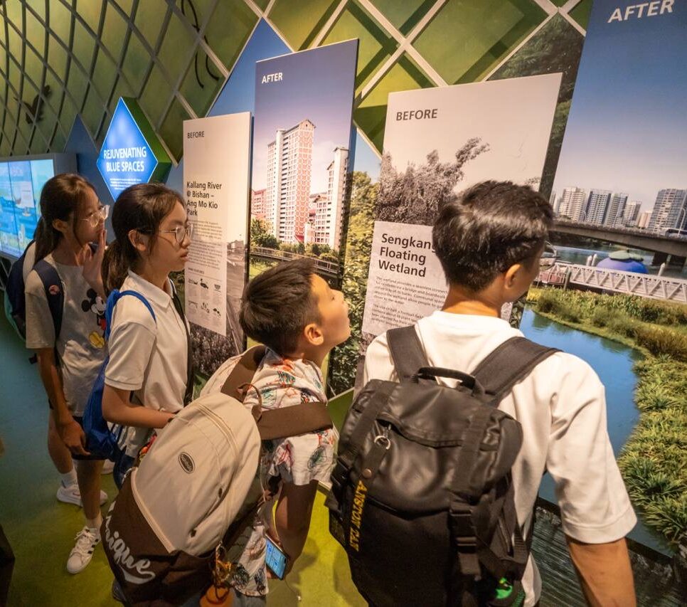 A group of people engages with educational displays about the Sengkang Floating Wetland in an exhibition space, offering insight into Singapore's innovative environmental efforts.