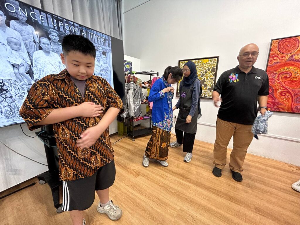 In an interactive cultural immersion workshop, students try on batik-patterned clothing for the first time. The workshop trainer gives a heritage commentary on the traditional customs of Malays in Singapore.